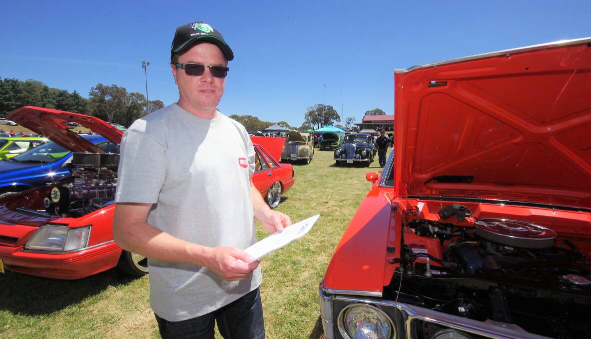 KEEN EYE FOR DETAIL: Simon Clarke with the scrutineers' sheet inspects one of the vehicles entered in the show and shine at the Can Assist car and bike show on Saturday. Photo: Darryl Fernance