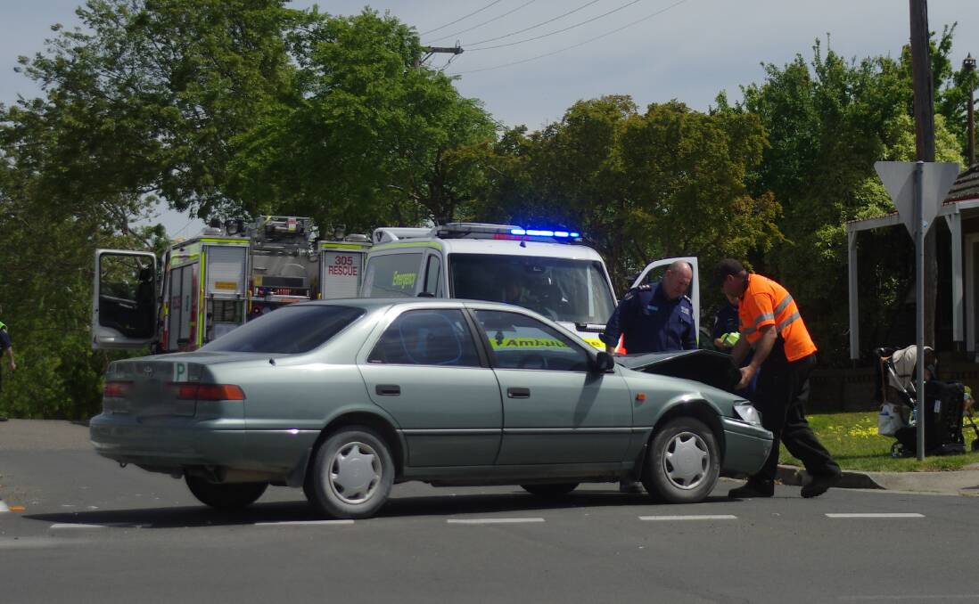MAKING SAFE TO MOVE: Fire brigade personnel and the tow truck driver make the Camray safe before moving it from the intersection: Photo Darryl Fernance
