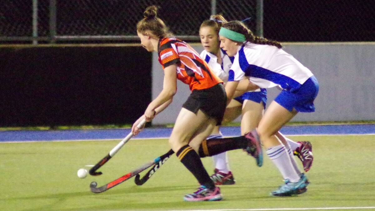 CLOSE CONTESTING: A Taralga player runs the ball down down the sideline tailed by two Ajax opponents in the first grand grand final of the Goulburn Hockey Association's fianle weekend. Photo: Darryl Fernance



