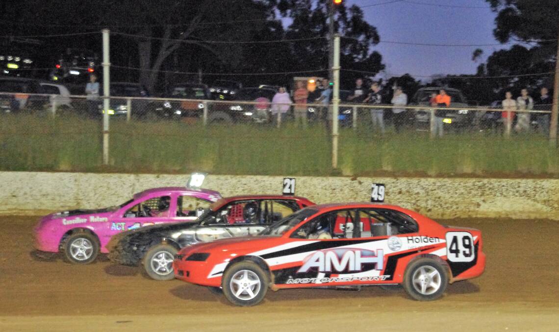 THREE WIDE: South Coast Production Sedan driver Johnny Ralph takes the inside line onto the front straight during the Christmas Cup meeting at Goulburn Speedway. Photo: Darryl Fernance