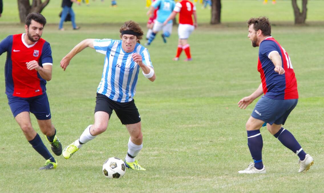 WITHSTANDING: Edan Wheeldon withstands a double challenge from the Pumas FC State League two players, in the Stags 3-1 winning game in Goulburn on May 6. Photo: Darryl Fernance