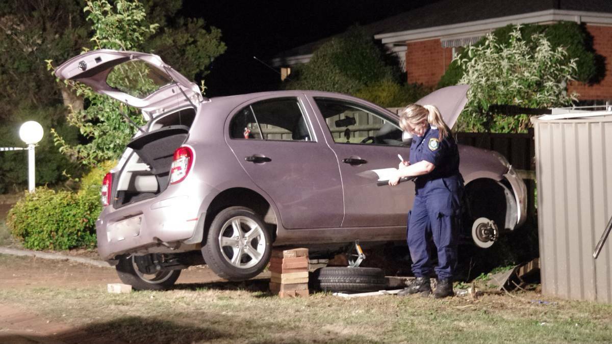 EXAMINING: Forensic officer Sergeant Nicole Brown examines the car underwhich the man had been trapped. Photo: Darryl Fernance