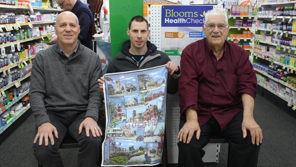 COLOURFUL: Peter and Matthew Blematl and artist Jean Pierre Favre with the Goulburn tea-towel in Blooms Chemist. 
