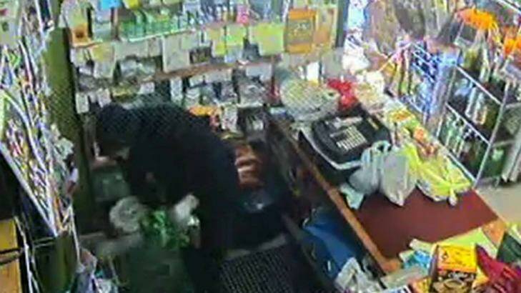 A security camera captured one of the thieves stealing cash from behind the counter. Photo: NSW Police