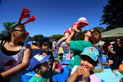Sharon Gibbons holds up her ten-month-old granddaughter, Sophie, while her other grandchildren look on, including Rebecca, wearing a Rudolf nose and Christmas antlers, before Carols In The Domain. Photo: James Alcock