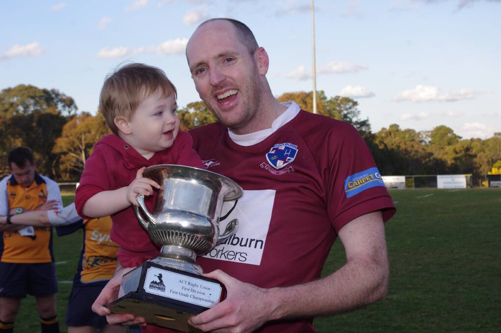 END OF AN ERA FOR ROB SHEEKEY (above): “After 28 straight years of playing some type of footy the body has had enough,” he posted on Facebook but he goes out on a high after being in the team that went through two seasons undefeated including the grand finals. He is pictured with his son Elijah on Saturday holding the Premiership Trophy.