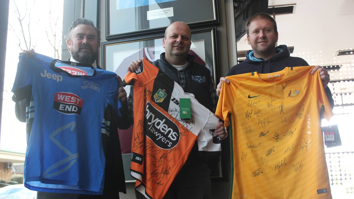 CALL OUT: Goulburn Stags Football Club members Brandon Doggett (left), Craig Norris and Ricky Eddy show off the signed Adelaide Strikers cricket jersey, Wests Tigers NRL jersey and a Socceroos jersey that will be up for grabs at an auction for their ‘Call to Arms Enchantment Under the Sea Ball next Saturday, August 6. 