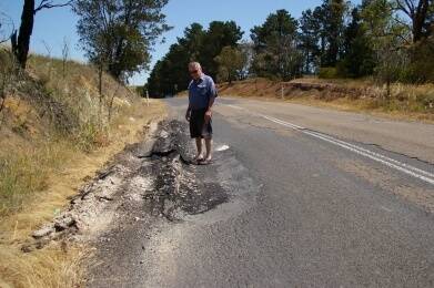 HIGHWAY TO HELL: Upper Lachlan Unsealed Roads Committee member and local resident John Kowalenko standing in a pothole along Taralga Road, which residents are calling "deplorable". Photo Darryl Fernance.