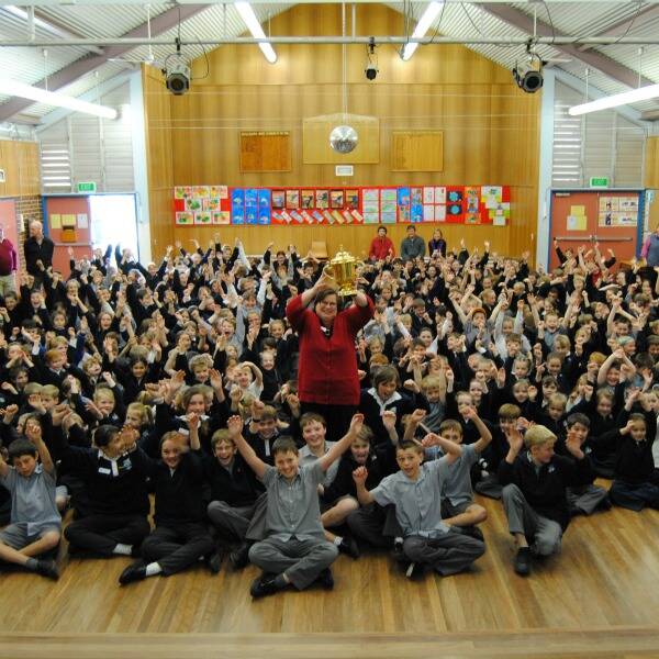 Principal of Goulburn West Public School, Annette Broadbent holds up the Webb Ellis Cup amongst a sea of students.