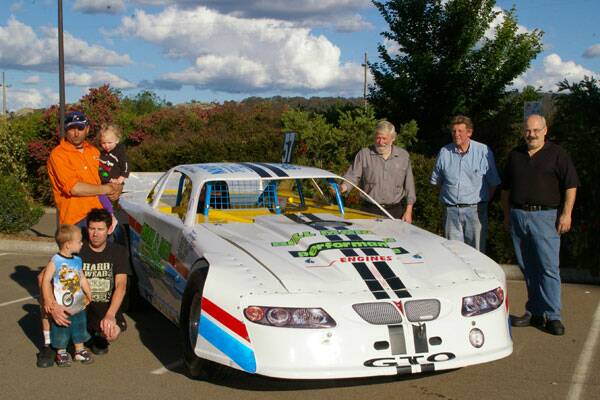 Paul Kranitis (standing left) with his daughter Charlotte, and sponsors Damien McAlister (crouching) and son Toby, Brian McAlister, Bill Martin and Peter Kontos beside the Chev V8 powered Super Sedan that will be racing in the NSW titles at Parramatta City Raceway tomorrow night.