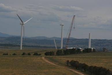 UP THEY GO: A giant 600-tonne capacity crane stands head and shoulders above the 80 metre tall wind farm towers as it lifts componentary into place in one of the district's biggest engineering projects.