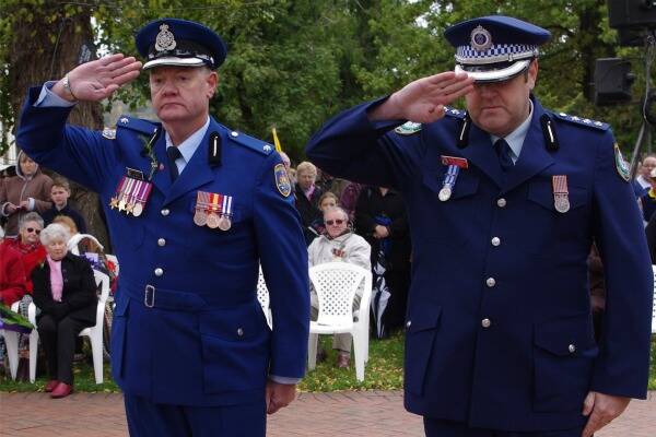 Corrective Services representative Alex Oliver and Goulburn Police duty officer Inspector John Sheehan salute after laying wreaths. 