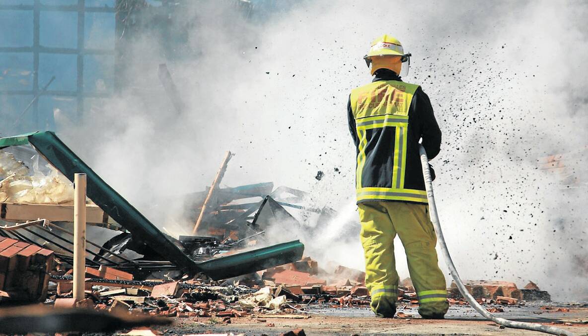 • A Yass fire fighter douses the smouldering rubble from November's Yass High School fire. THE Goulburn tip could be receiving asbestos affected building material from Yass over the next month. Photo courtesy YASS TRIBUNE.