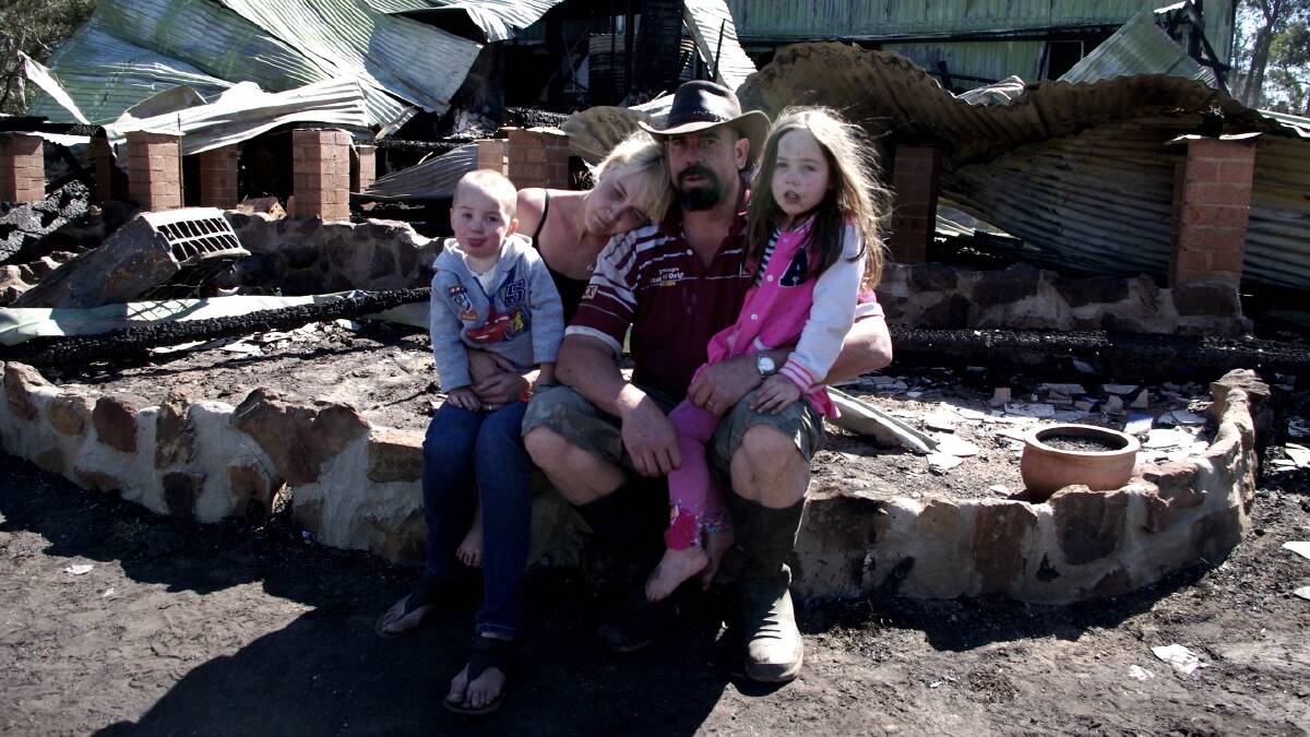 Ross and Deborah Robinson comfort their children Callum and Isabella as they sit among the ashes that were once their family home. Photo: Darryl Fernance 