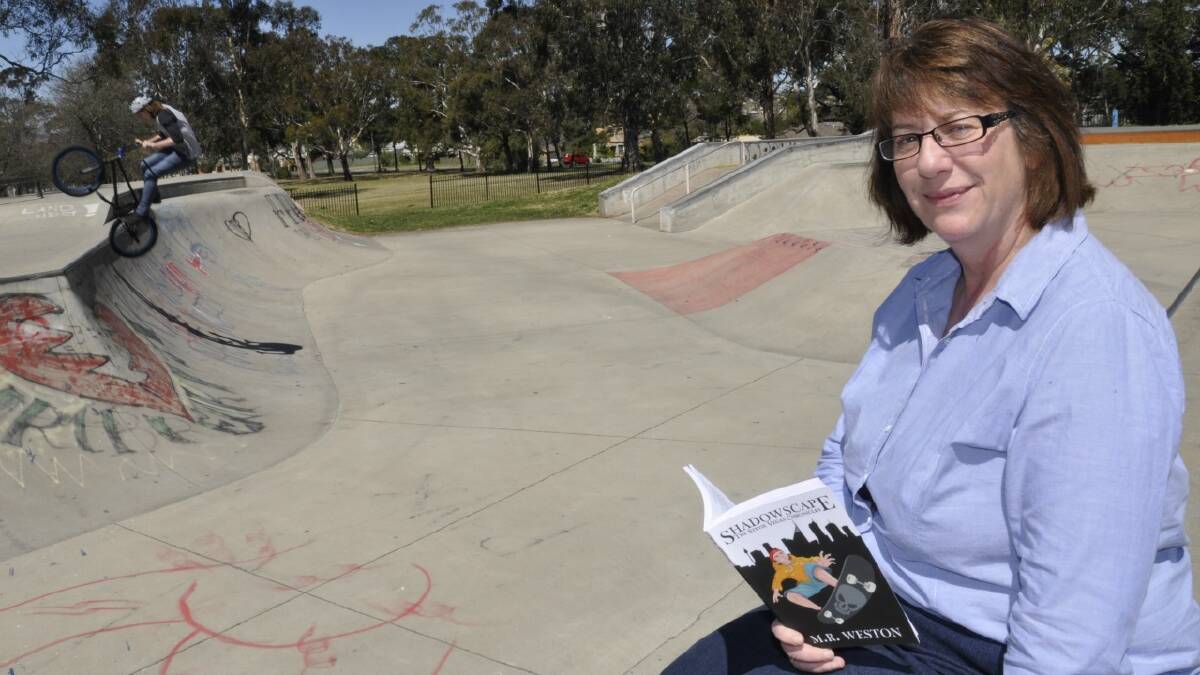 STRONG MESSAGE: Former Goulburn Post editor Maryann Weston has written her first book ‘Shadowscape: The Stevie Vegas Chronicles’ about a young skateboarder who combats bullying. The work, aimed at nine to 14-year-olds, was released last Monday. In the background, 17-year-old Blair Hill works his magic at the Goulburn skate park 
