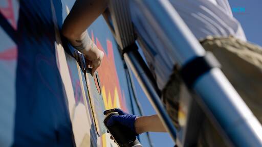 Street artist completing a mural. Picture via Canva.