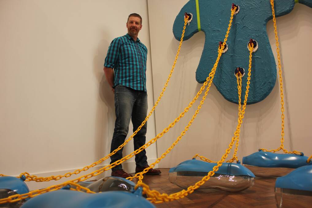 TWO WORLDS: Goulburn Regional Art Gallery curator and exhibitions officer Andre de Borde alongside Scott Chaseling's work. Photo: Mariam Koslay. 