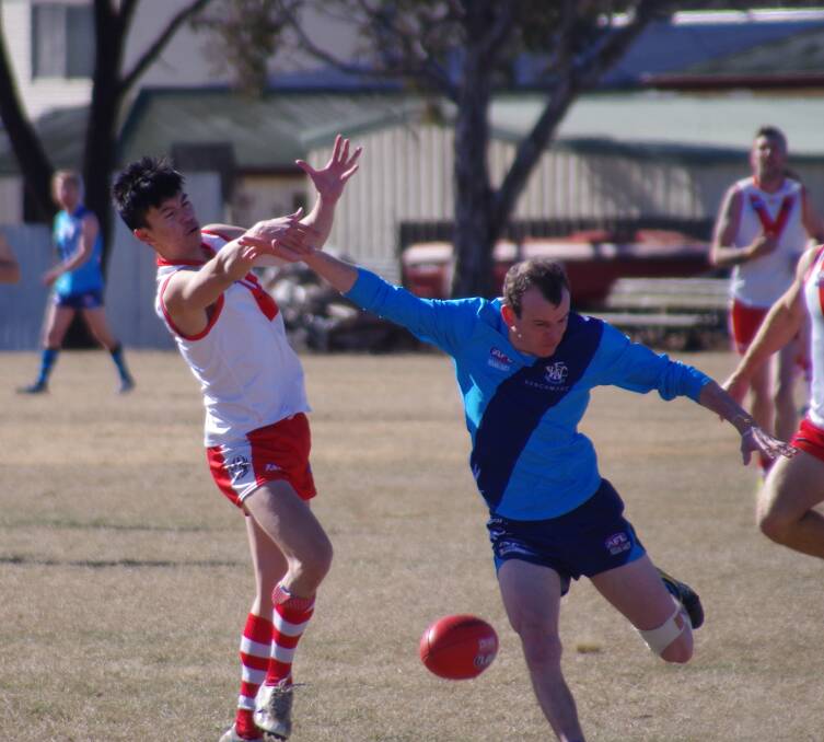 HINDERED: Goulburn's Phill Nguyen being spoiled by a Woden player during the heated first quarter of the game on Goodhew Park. Photo: Darryl Fernance