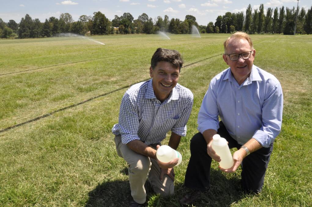 GOING GREEN: Hume MP Angus Taylor and Mayor Bob Kirk at Carr Confoy fields on Wednesday where the water re-use scheme will be deployed. The men are holding bottled non-potable water from the new wastewater treatment plant. Photo: Louise Thrower.