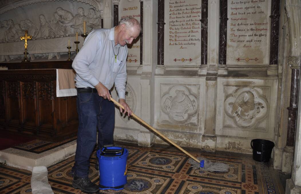 St Saviour's Cathedral parishioner John McCulloch gets to work after heavy rain came through downpipes into the sacristy. Photo: Louise Thrower.
