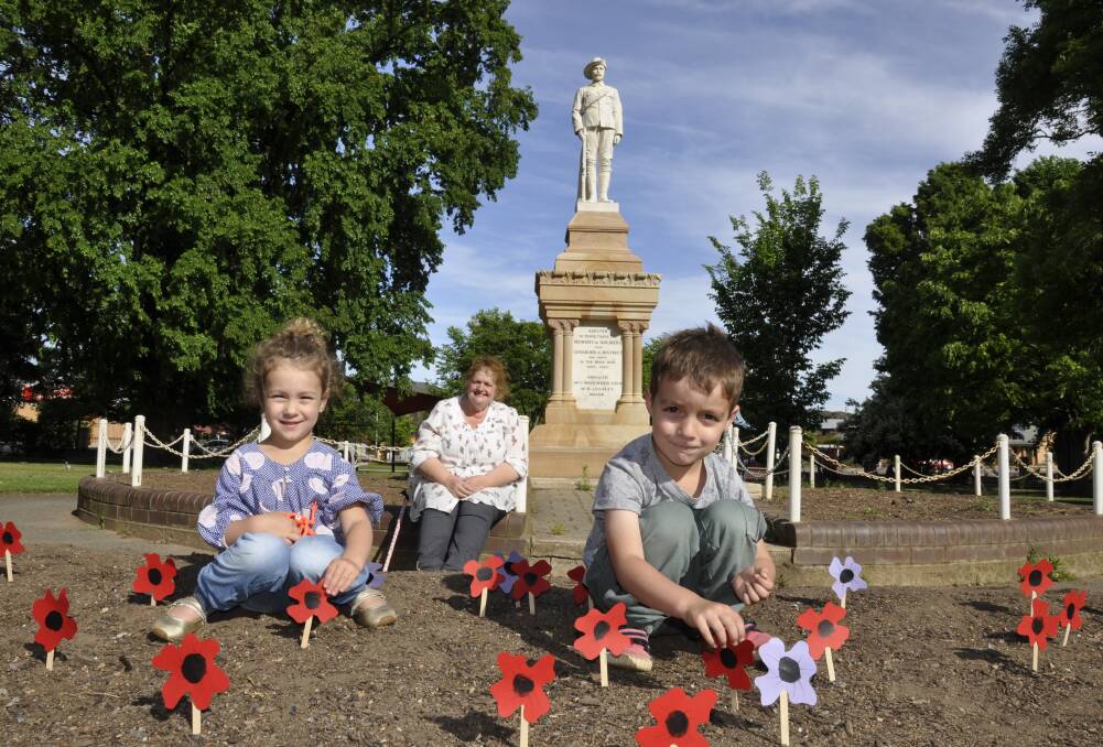 Three-year-old Emily Stephens and brother Henry, five, gained a glimpse into the importance of Remembrance Day by helping their grandmother Liz Reilly place paper poppies in Belmore Park on Friday. Photo: Louise Thrower.