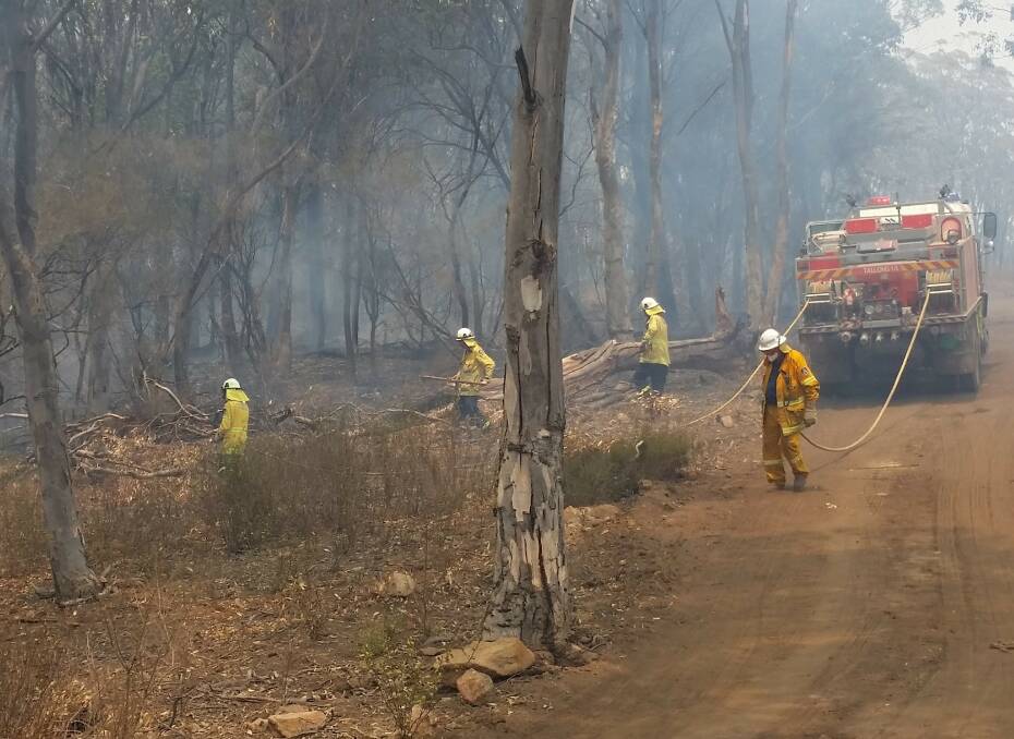 Tallong RFS dousing hot spots from the Caoura Road fire which was burning in the gorge below last week. It has since become part of the Currowan blaze. Photo: Tallong RFS.