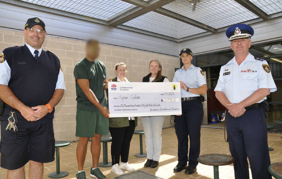 A Goulburn Correctional Centre inmate was proud to hand over a $2758 'cheque' to Anglicare regional manager of housing and homelessness, Tony Reay and coordinator, Donna Cutmore. Also on hand were corrections officers, Frazer Kerr (left), Stephanie Bauche and governor, Paul Coyne. Picture by Louise Thrower.