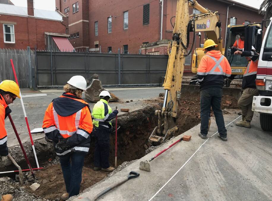 Archaeologist Wendy Thorpe (green jacket) inspects stonework found during excavations to relocate a sewer line to facilitate Goulburn's new performing arts centre. Photo: David Cole.