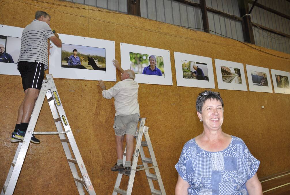 Goulburn AP&H Society president Jacki Waugh was busy as a bee on Monday setting up for the weekend's annual show. At rear, Ross Webster and Adrian Doran mount the Portraits on Main exhibition. Picture by Louise Thrower.
