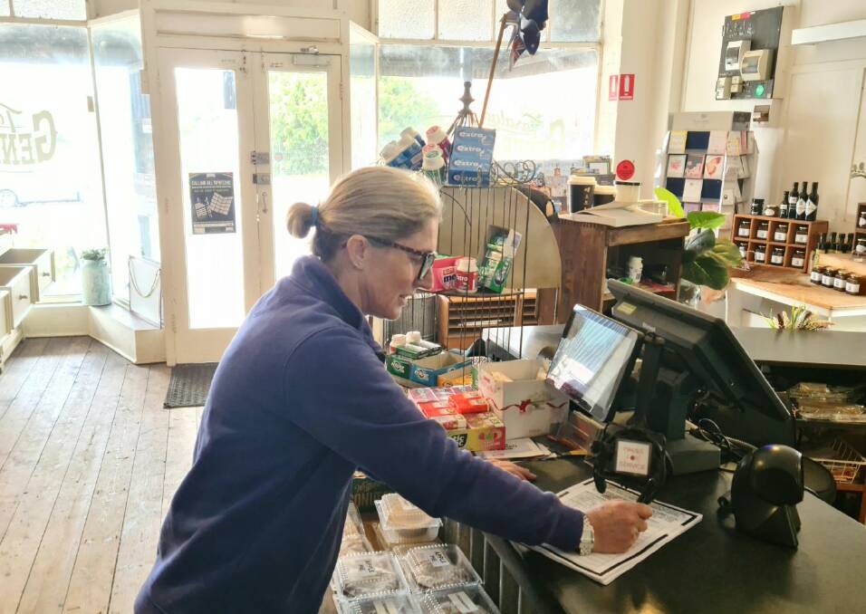Taralga General Store sales assistant, Gabi Keith, signs a petition opposing Upper Lachlan Shire Council's withdrawal from the town's Post Office contract. Picture supplied.