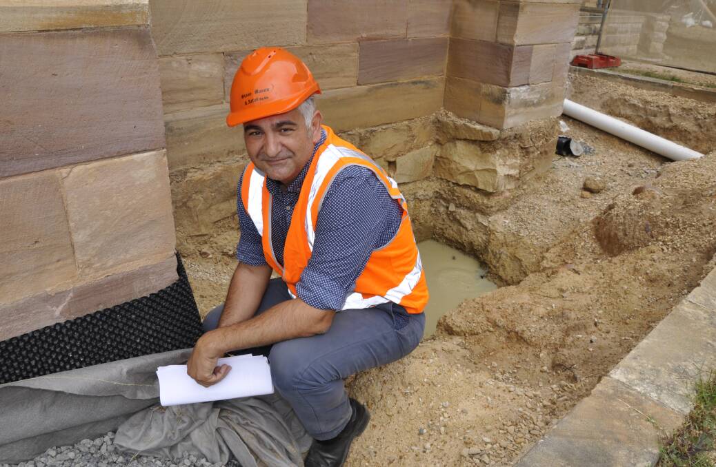 Stonemason and Artist Pty Ltd project manager George Parasiris has injected his expertise into the restoration. He shows off the aggregate drain and trench around the cathedral.