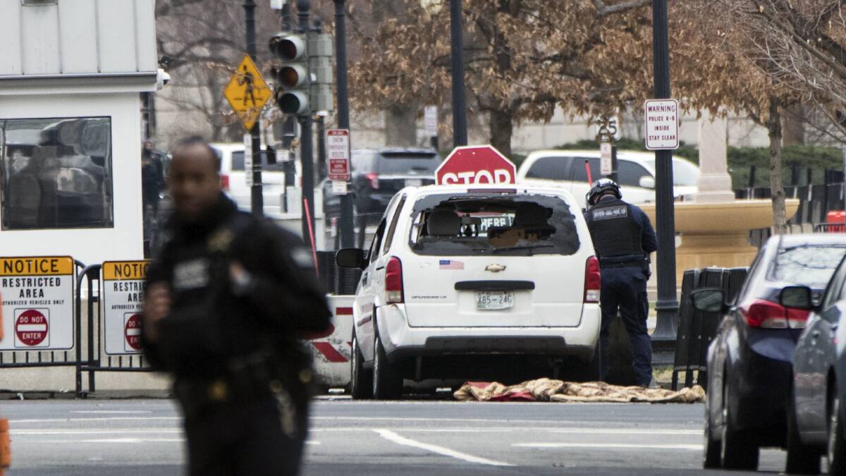 A Secret Service officer checks a white passenger vehicle that struck a security barrier a the southwest entrance to the White House grounds off of 17th Street n Washington, Friday, Feb. 23, 2018.Picture: AP
