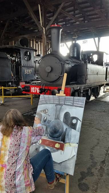 Di Smith painting the iconic 1076 steam engine at the Goulburn Loco Roundhouse. Image supplied. 