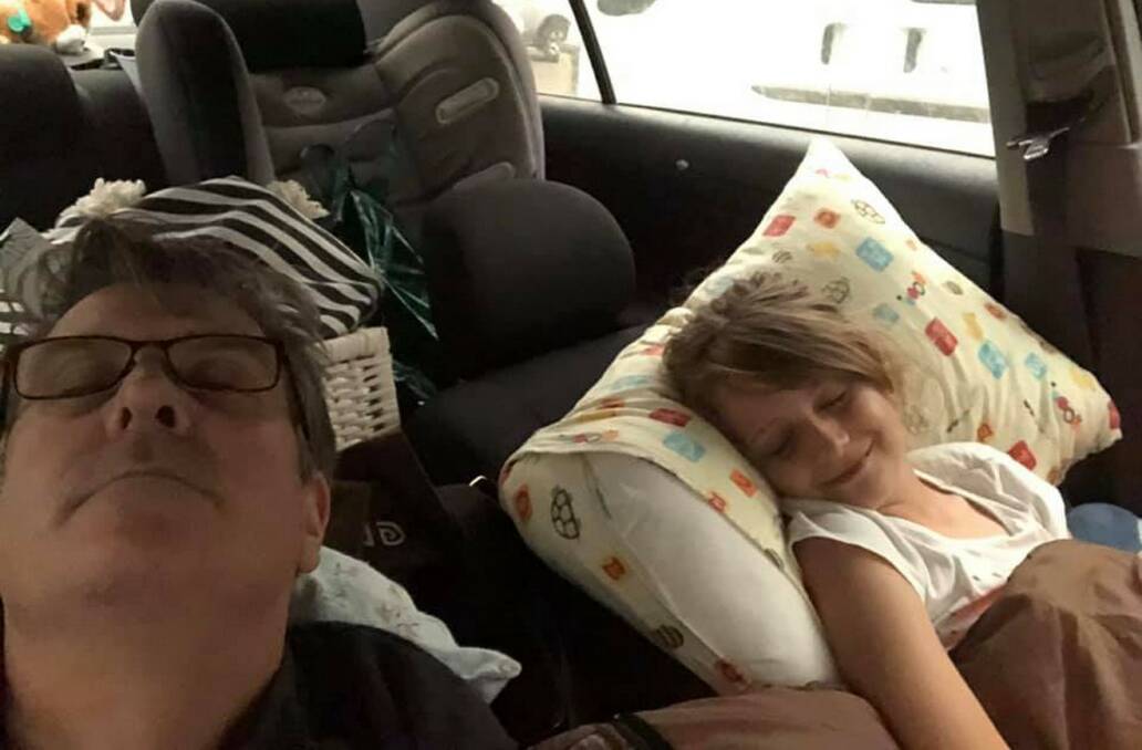 Peter Bayliss asleep in his van in a car park at Ulladulla with his daughter Anwyn. The family of four children and two adults had to sleep in the van for two nights. Photos supplied. 