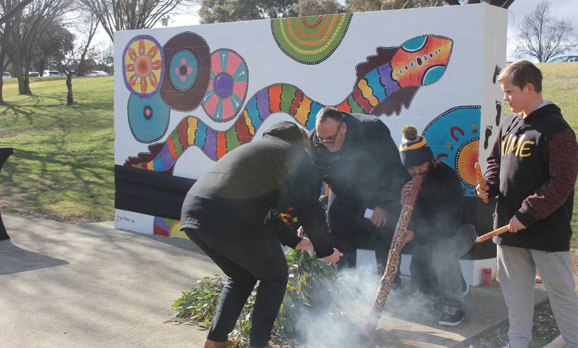 SMOKING CEREMONY: Cr Alf Walker conducting a smoking ceremony at the opening of the mural with Joseph Chapman-Freeman playing didgeridoo and Luke Heitel-Freeman on clapping sticks. Photo Burney Wong.