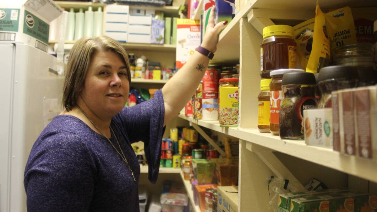 STOCKING UP: Anglicare staff member Tracey Roberts stocking the shelves with food donations on Friday. Photo: Mariam Koslay