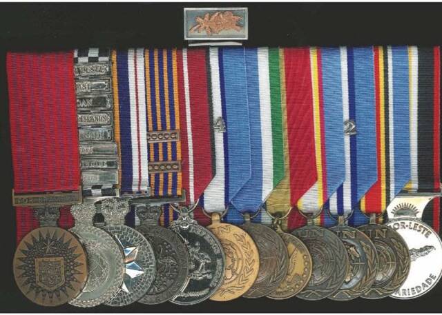 Medals held by Police peacekeeping veteran Paul McEwan. From left - Bravery Medal (BM); POSM with eight clasps, CYPRUS, MOZAMBIQUE, HAITI, EAST TIMOR, SOLOMON ISLANDS, RAMSI, SUDAN, TIMOR LESTE; National Police Service Medal; National Medal with two clasps; Australian Defence Medal; UN Medals for Cyprus and Mozambique; Medal for Service in Haiti (US); UN Medals for East Timor (UNAMET), Sudan(UNMIS) and East Timor (UNMIT); Timor Leste Solidarity Medal; with Group Bravery Citation. Photo: Supplied. 