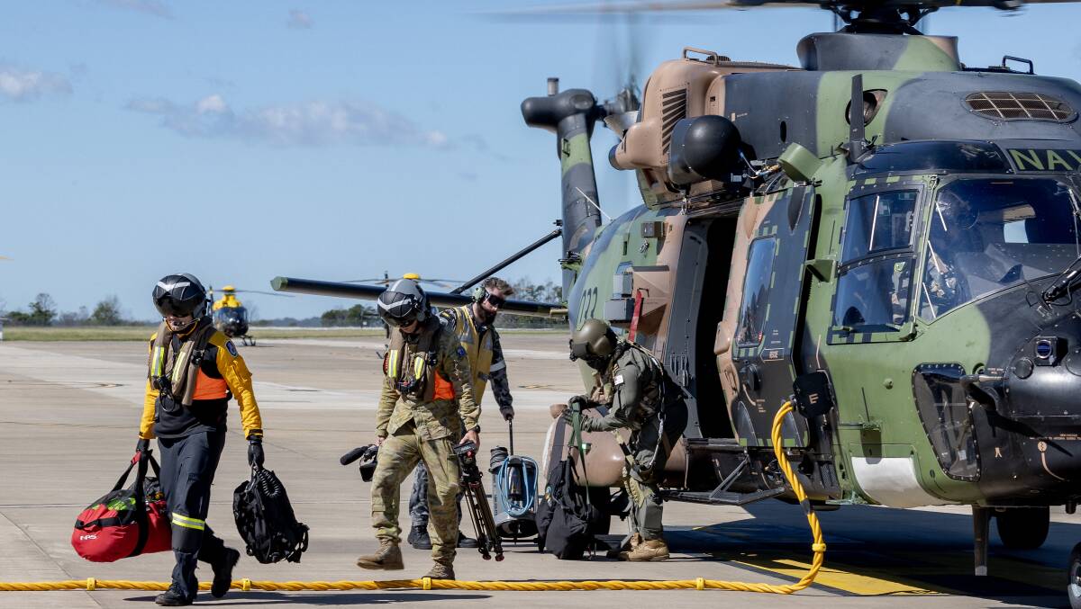 HOME: A NSW Rural Fire and Rescue member and ADF personnel return to HMAS Albatross on the completion of a successful search and rescue mission during Operation NSW Flood Assist. Photo:John Solomon