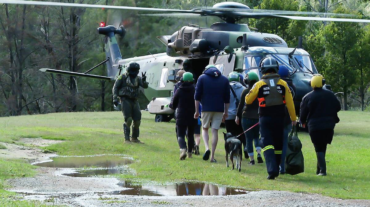 SAFE: An 808 Squadron Aircrewman and RFS member escort rescued hikers in the Wollondilly Forest during Operation NSW Flood Assist. Photo: Defence