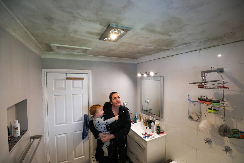 Sickening: Renee Ellington with her son son Greyson Onley, 1, in the bathroom of their rental home in Albion Park. Sadly this isn't the only part of the rental property with black mould of this severity. Picture: Adam McLean