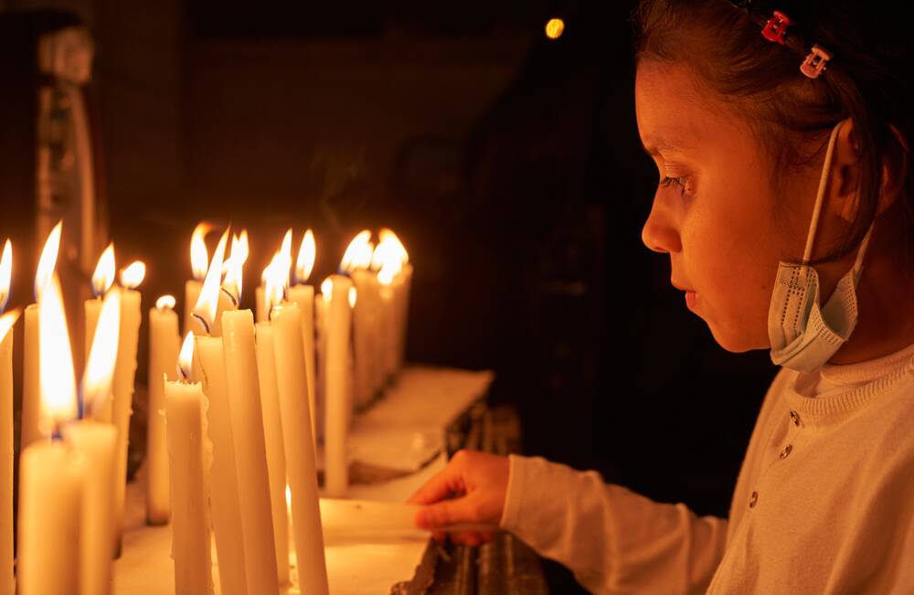 A child lights candles to illuminate her Bogota home. Picture Shutterstock