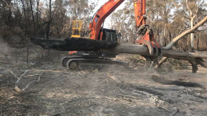 Using a break in the weather to clear away smouldering trees. Picture: Robbie Wallace