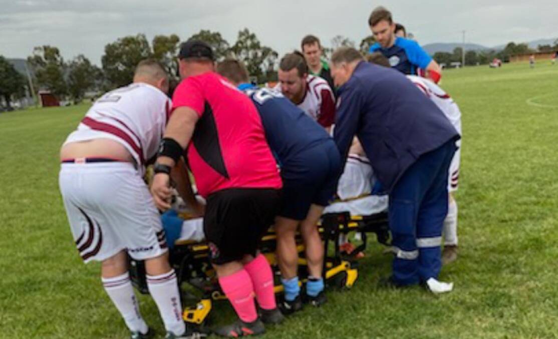 All involved: Players from both teams, officials, and spectators rushed to help Hartin after a bad tackle left him with a broken leg. Photo: Goulburn Strikers FC. 