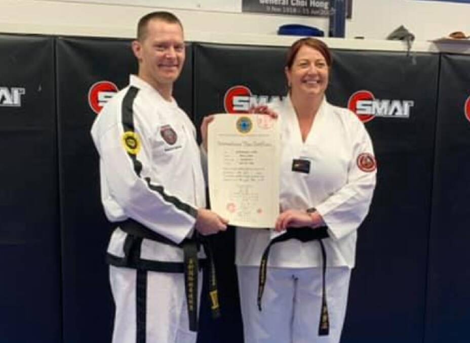Hard-earned: Craig Harmer presents Mel Bell with her blackbelt certificate last week. Photo: Goulburn Martial Arts Academy. 