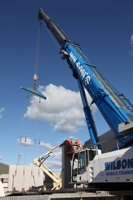 UP IN THE BIG BLUE: A 350 tonne crane lowers one of the pre-fabricated concrete walls into place at the Aldi site in Auburn St.