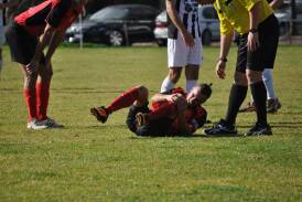 A Queanbeyan City player goes down injured during their semi-final loss to Weston-Molonglo a fortnight ago. Photo: Capital Football.