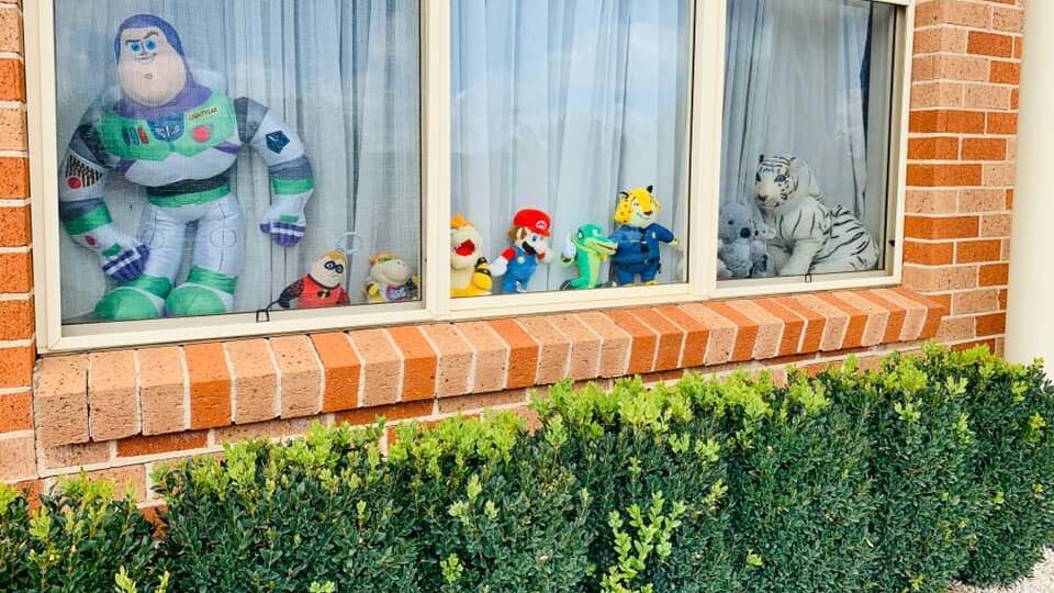Buzz Lightyear and Mario peer out the window with their teddy friends.