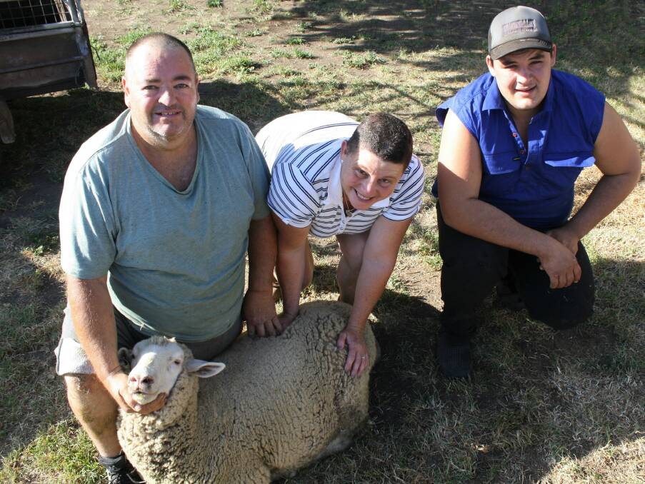 Wayne and Kathy Dowling and Peter Johnson with one of their remaining sheep. Photo: Hannah Sparks