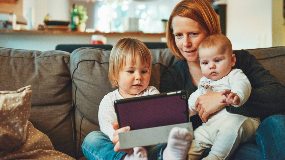 STAYING CONNECTED: A mother and her two young children record a video message to send to a relative. Photo: Alexander Dummer