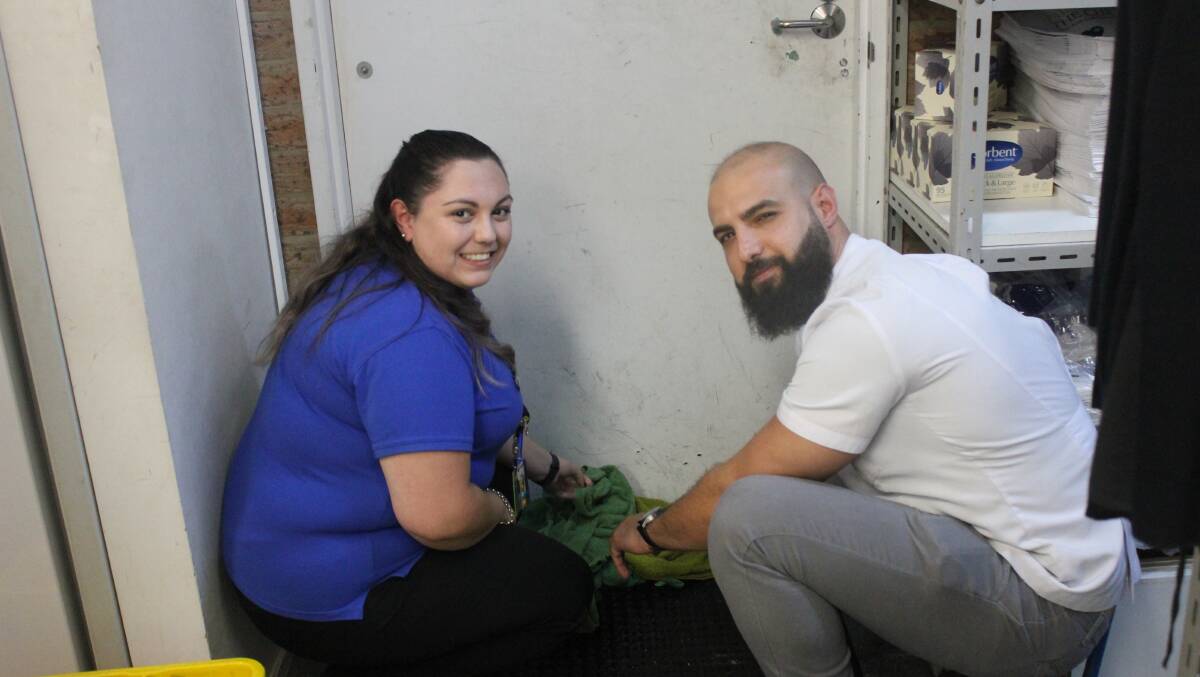 Blooms the Chemist workers Natalie Long and Hassan Ajami tending to the water flooding through the back door. 